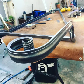 Skilled craftsman working on custom ornamental ironwork in workshop