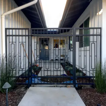 Skilled welder fabricating ornate wrought iron gate with decorative scrollwork in workshop