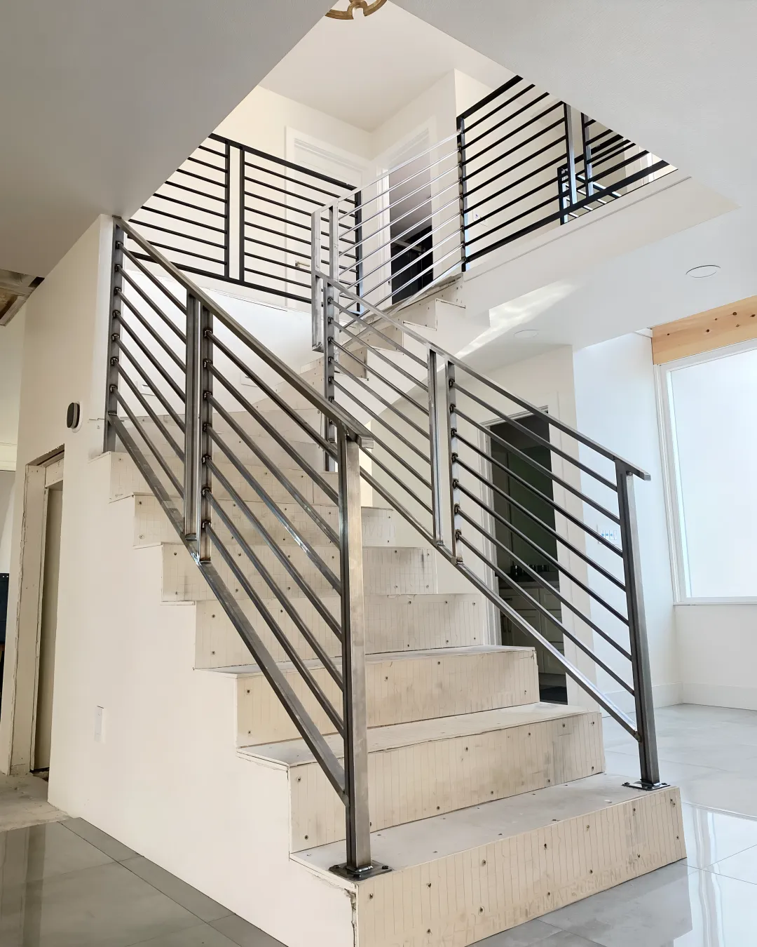 Professional craftsman installing custom wooden stair treads with iron railings