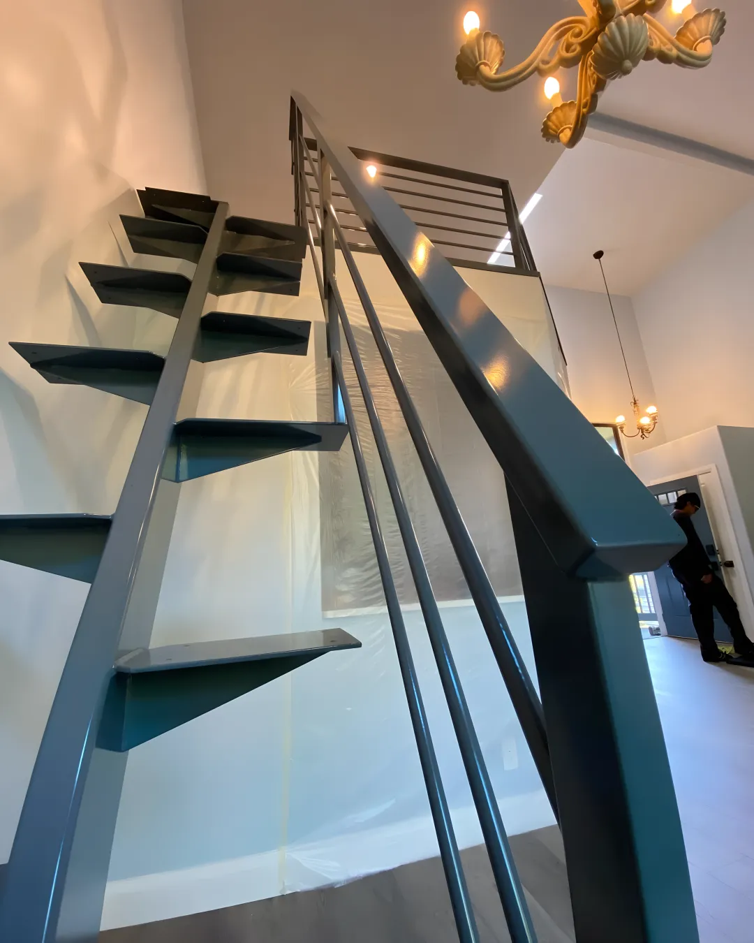 Skilled welder fabricating ornate wrought iron staircase components in workshop