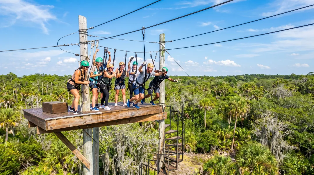 Corporate group zip lining over Florida wildlife preserve on outdoor adventure activity