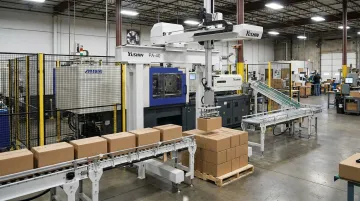 Yushin PA Series compact palletizer stacking boxes at end of injection molding line